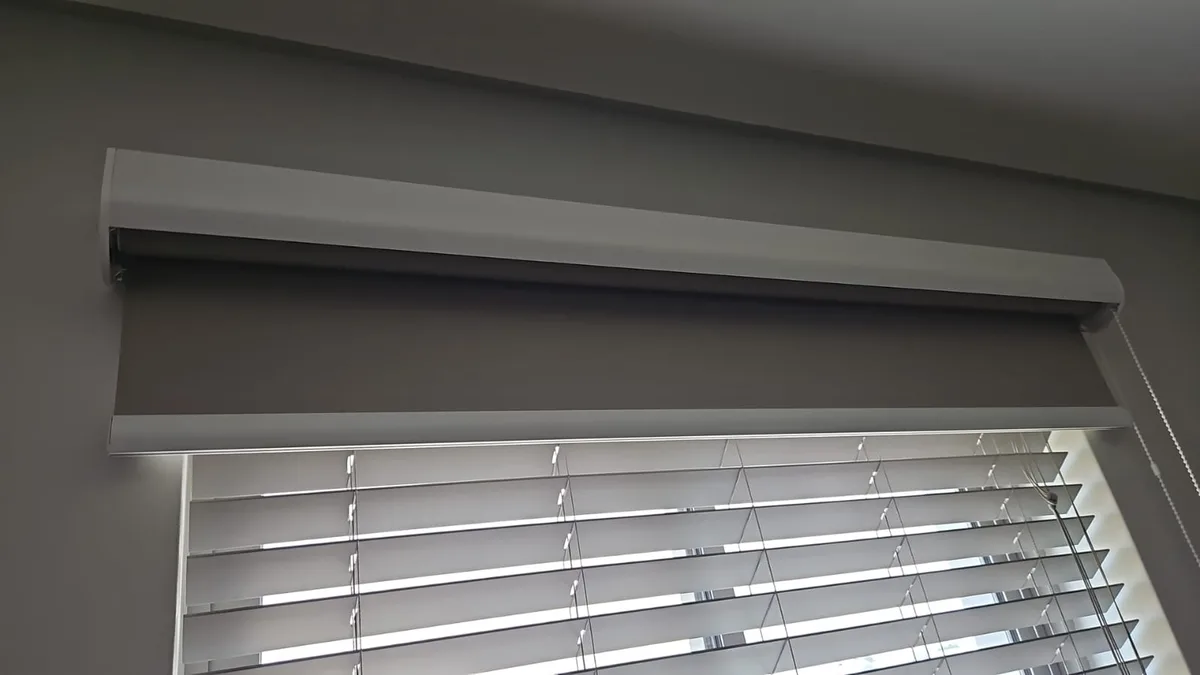 Opaque blockout roller blind partially rolled up over a window