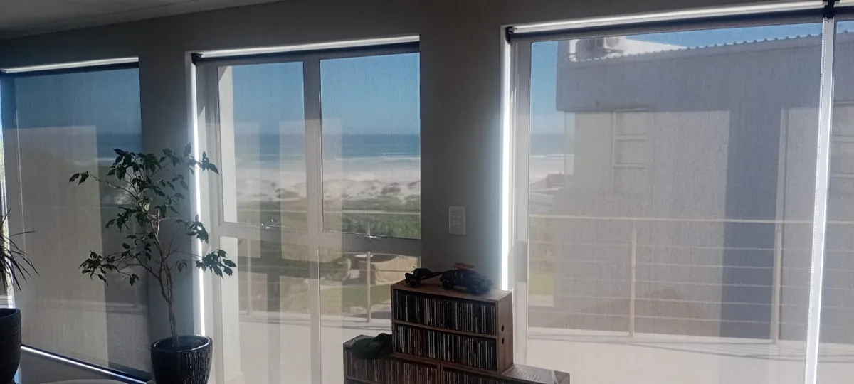 Perforated screen roller blinds with a beach and dune view