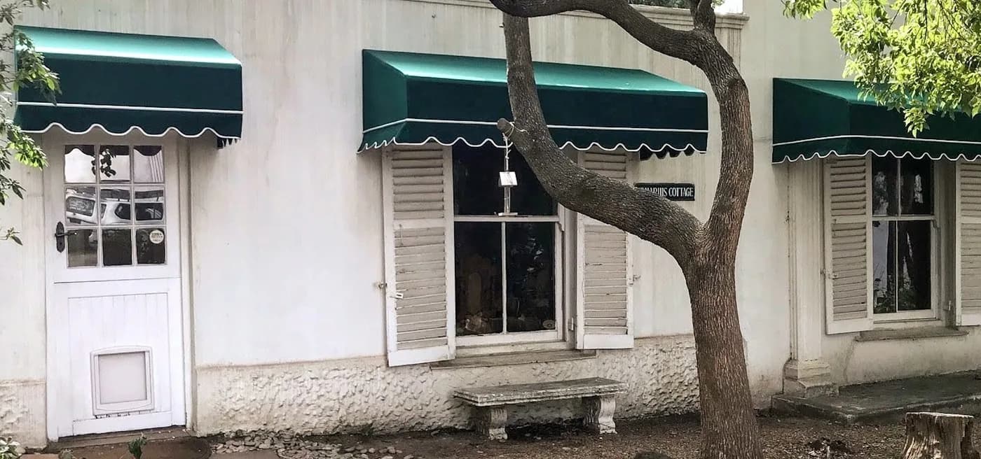 Three green box wedge awnings with scalloped valances over cottage windows